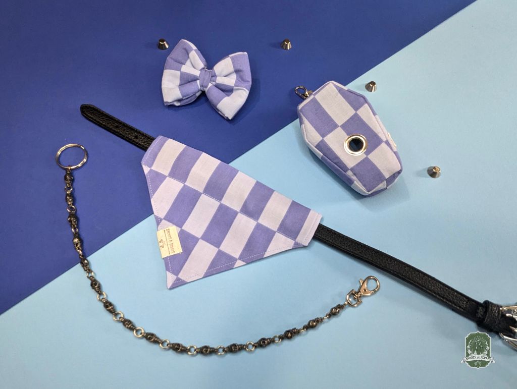 Pet accessories including a checkered bandana, bow tie, and collar on a blue and light blue background.