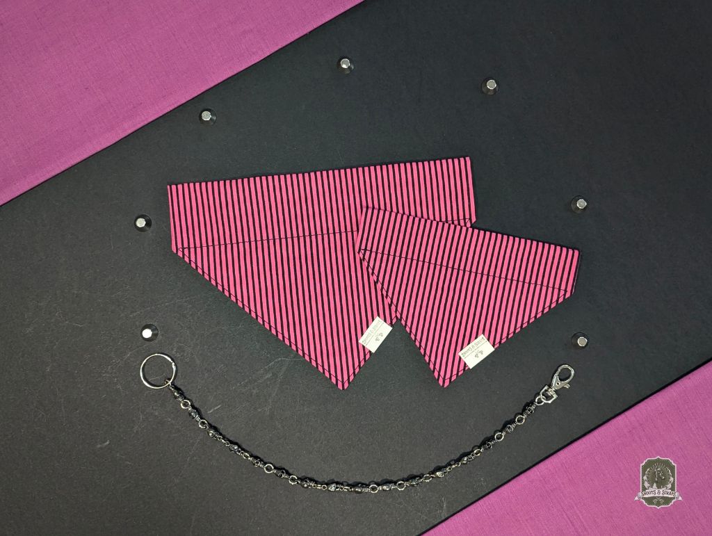 Pink and black striped dog bandana that slides onto a collar, with decorative chain on a black and pink background with bat decorations