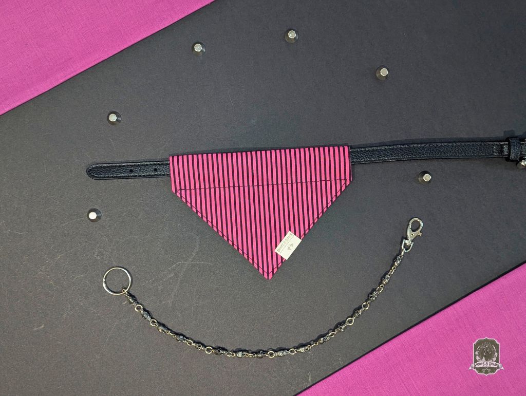 Pink dog bandana on a black collar and chain on a gray and pink background