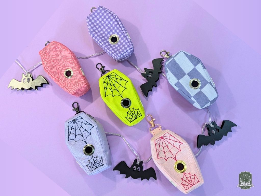 Set of colorful Halloween-themed poo bag dispensers on a purple background