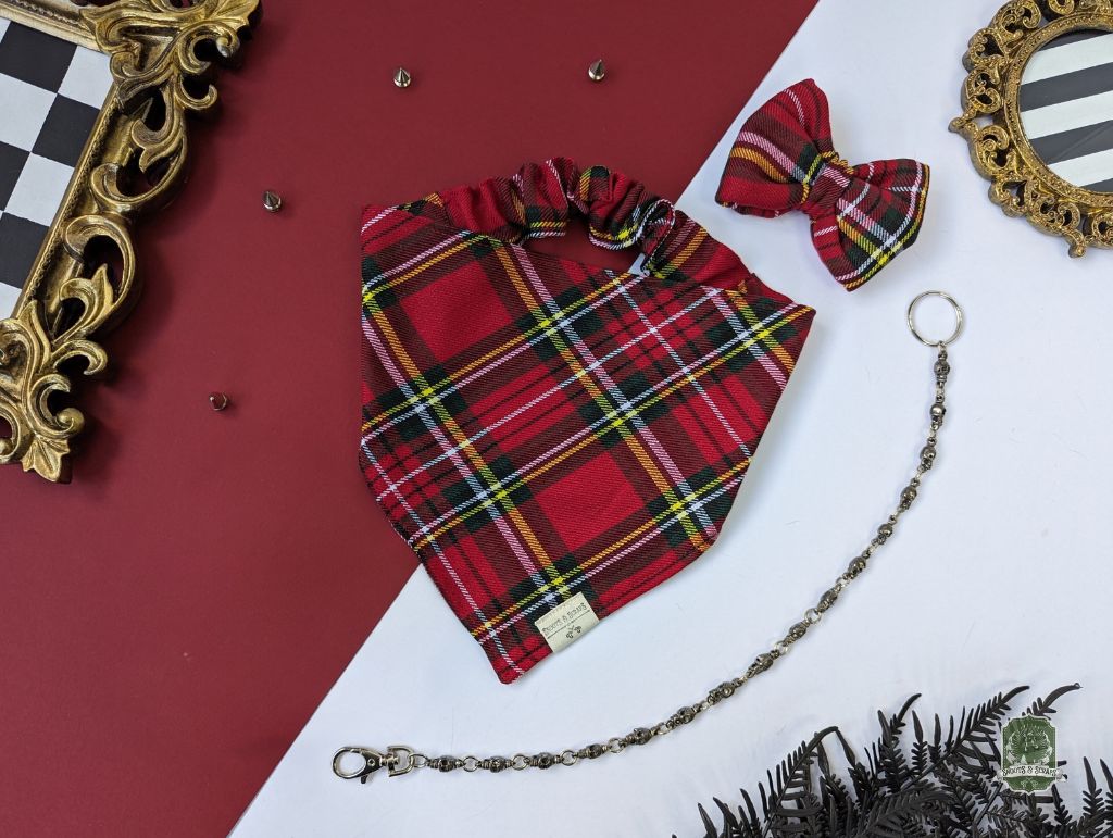 Red plaid dog bandana with matching bow and chain on a red and white background