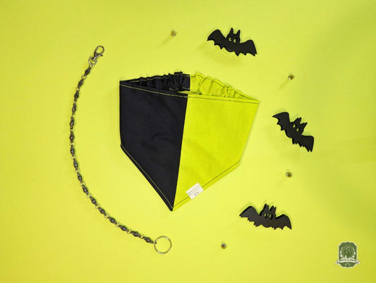 Black and lime green dog bandana on a yellow background with small black bats.