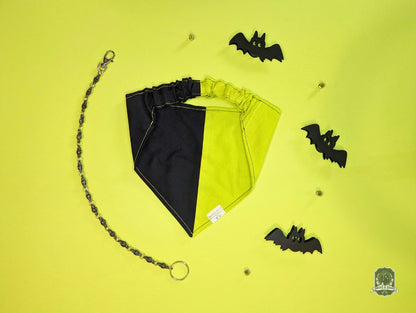 Black and acid yellow dog bandana with a chain on a yellow background with black bat decorations.