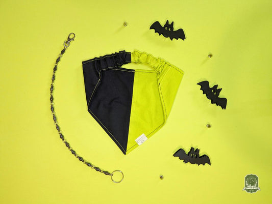 Black and acid yellow dog bandana with a chain on a yellow background with black bat decorations.