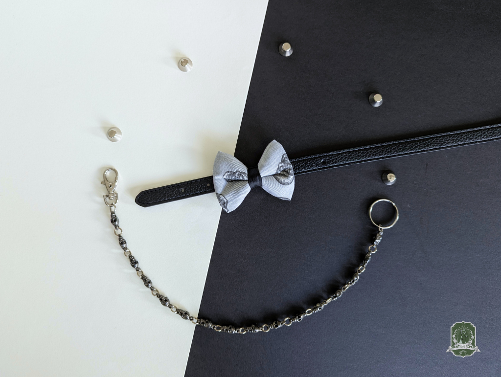 Grey skulls pattern cat bow tie displayed on black leather collar