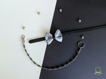 Grey skulls pattern cat bow tie displayed on black leather collar