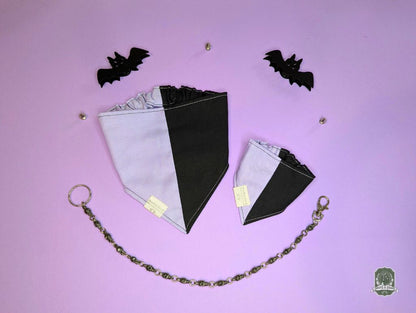 Dog bandana with black and lilac colour block design on a pink background with decorative bats.