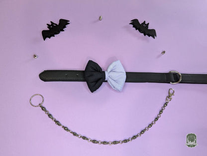 Black and lilac dog bow tie with a chain and bat-shaped accessories on a pink background