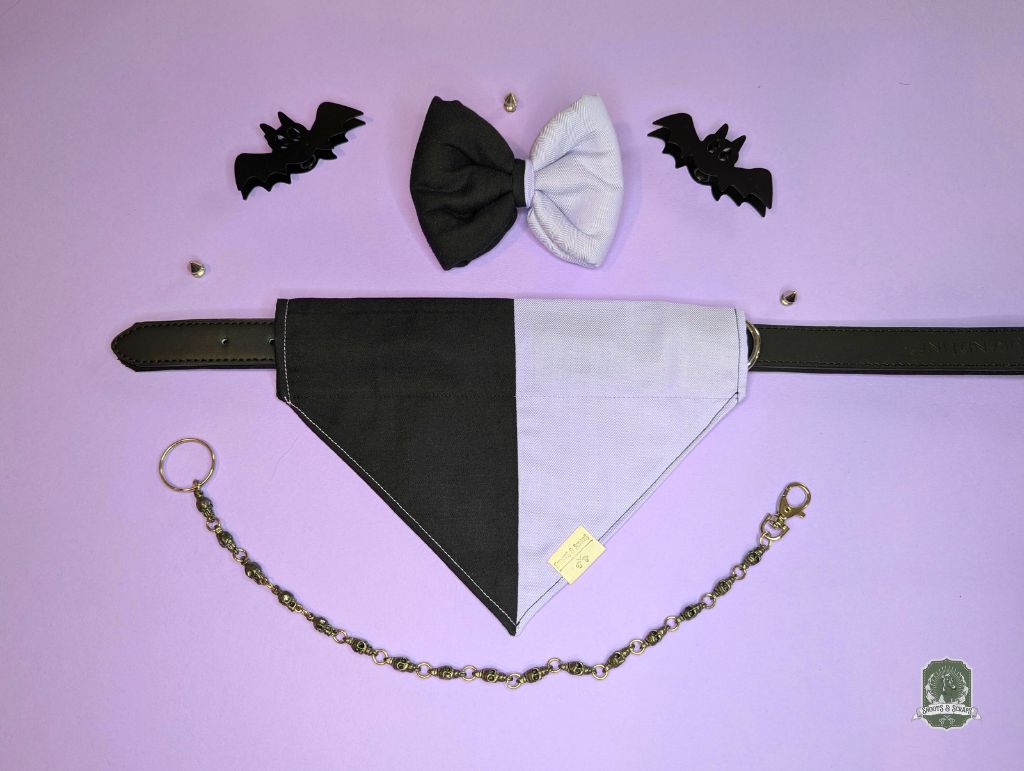 Black and lilac dog bandana with matching dog bow ties, and bat decorations on a purple background