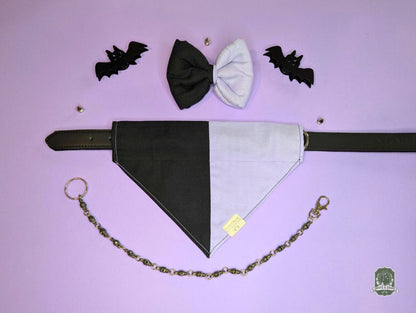 Black and lilac dog bandana with matching dog bow ties, and bat decorations on a purple background