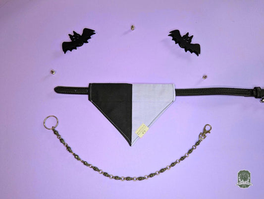 Black and lilac dog bandana with a chain on a purple background with bat decorations.