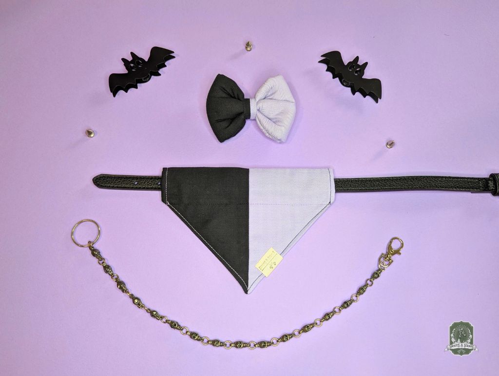 Pet accessory set with black and lilac bandana, bow tie, and decorative  chain on a purple background