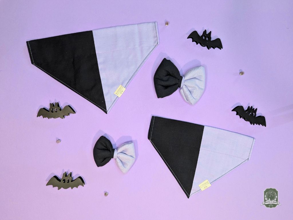 Black and lilac dog bandanas with matching dog bow ties on a purple background with bat shapes.