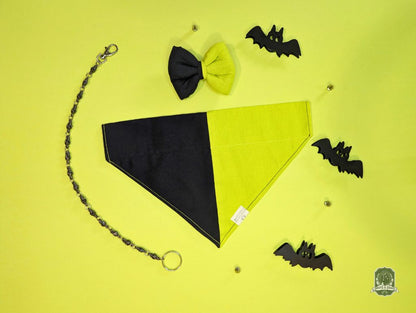 Halloween-themed pet accessories including a bandana, bow tie, and  decorative bats on a yellow background.