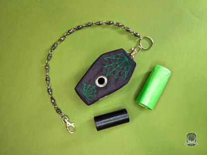 Black coffin-shaped dog poop bag holder with green spider web design on a green background