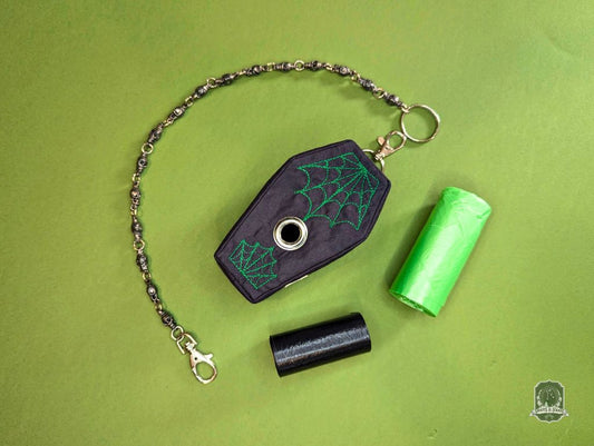 Black coffin-shaped dog poop bag holder with green spider web design on a green background