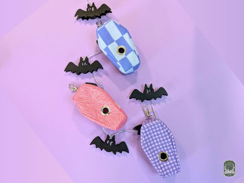 Pet accessory set of coffin shaped poop bag holders in pastel colours  on a purple background