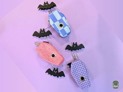 Pet accessory set of coffin shaped poop bag holders in pastel colours  on a purple background