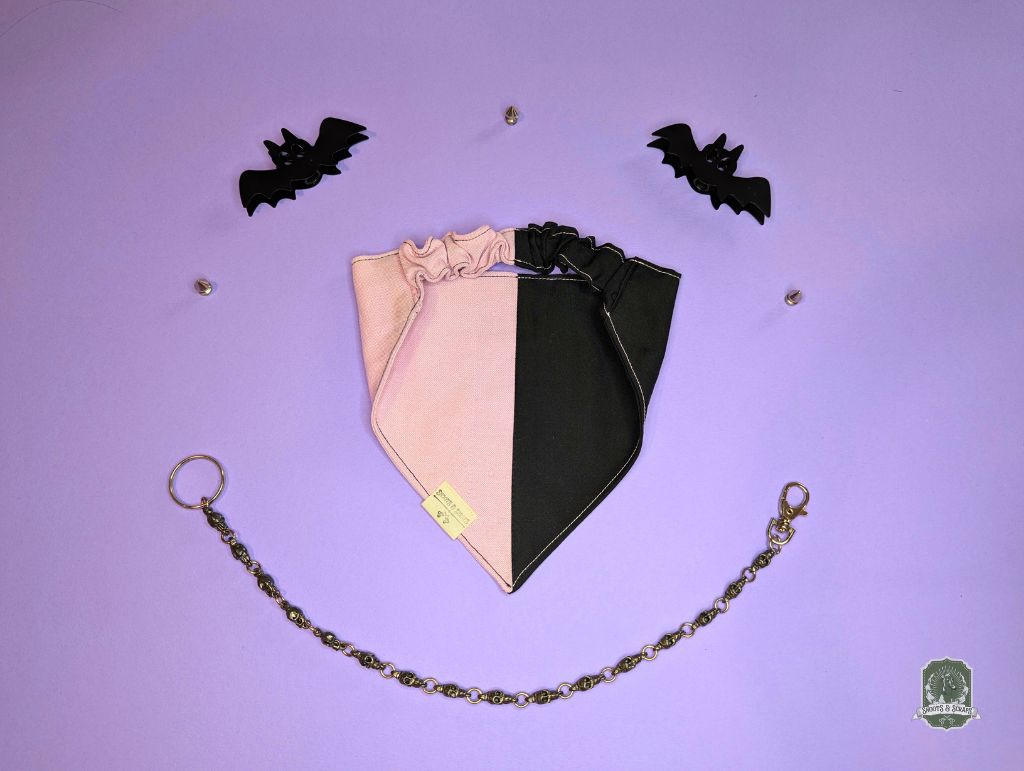 Two-tone pink and black elastic dog bandana on a purple background with decorative bats.