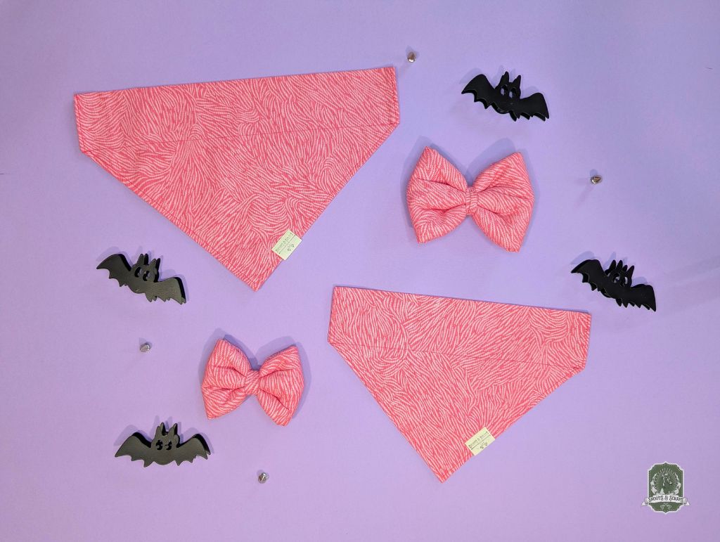 Pink zebra print dog bandanas and bow ties with black bats on a purple background