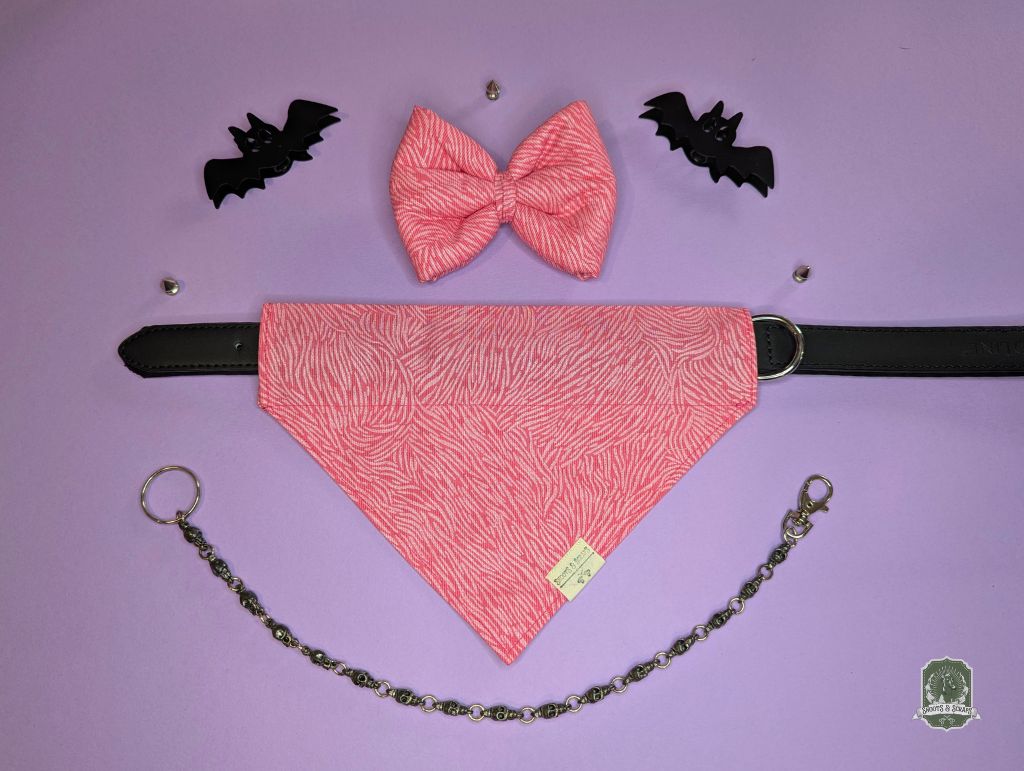 Pink dog bow tie and bandana set displayed with black leather collar on a purple background