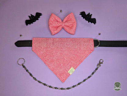 Pink dog bow tie and bandana set displayed with black leather collar on a purple background