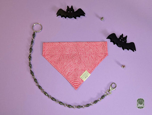 Pink zebra print dog bandana on a purple background with black bat decorations