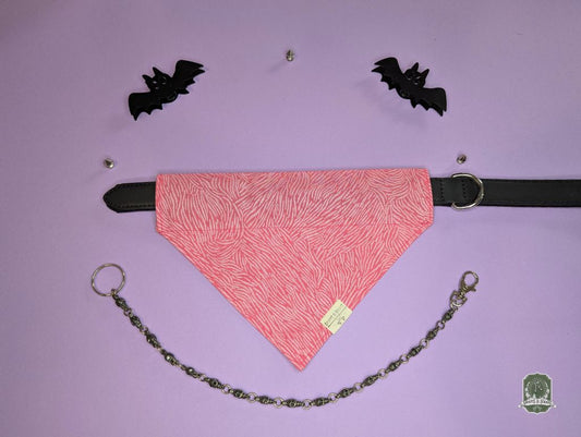 Pink zebra print dog bandana on a purple background with black bat decorations