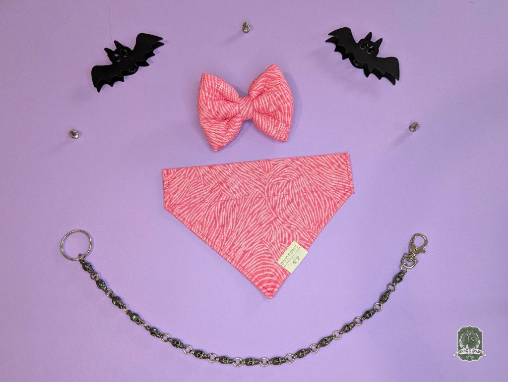 Pink zebra print dog bandana on a purple background with black bat decorations