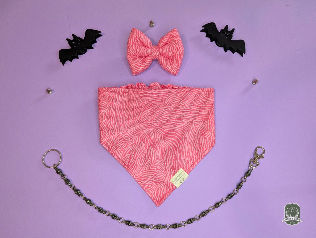Pink zebra print pet bow tie  set with matching dog bandana on a pastel pink background and decorative chain.